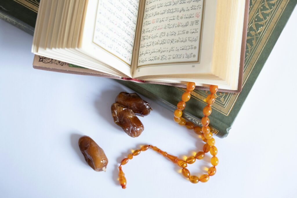 Open Quran with tasbih and dates on a white background, symbolizing spirituality and Islamic traditions.