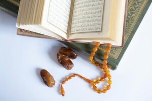 Open Quran with tasbih and dates on a white background, symbolizing spirituality and Islamic traditions.